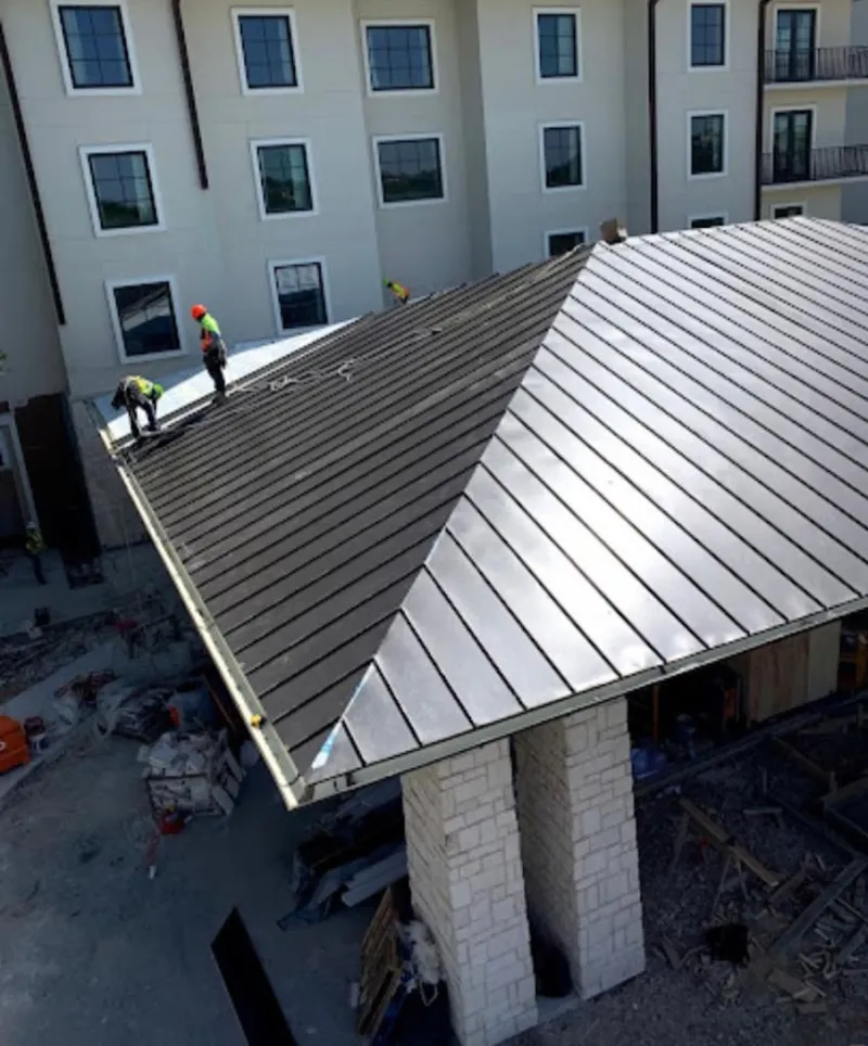 Crew installing standing seam metal roof panels on a commercial project in Calimesa